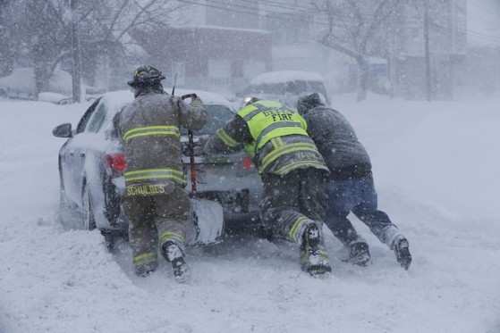 Bombeiros tentam retirar carro preso na neve em Buffalo nesta terça-feira (18)