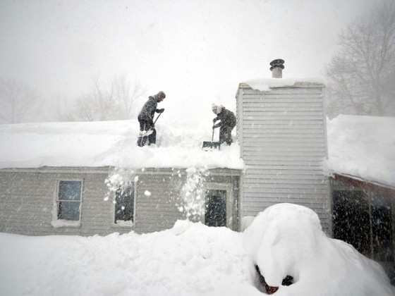 Tami Normile e Richard Brooks tentam tirar o excesso de neve do telhado de sua casa no subúrbio de Lakeview, em Buffalo, NY, na quinta-feira (20) 