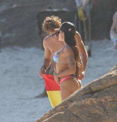 Casal beijando em areia de praia.