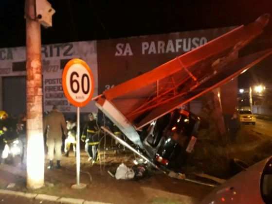 O motorista ficou preso às ferragens ao capotar carro e bater em estrutura metálica.