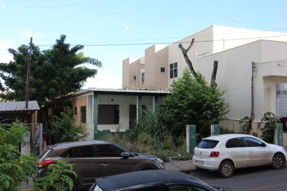 No local da sede da Importadora e Exportadora Jardim Cuiabá Ltda, há apenas uma casa sem portas e janelas, com pintura desgastada e rodeada por um matagal.