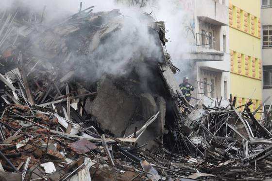 Bombeiros buscam por sobreviventes nos escombros.