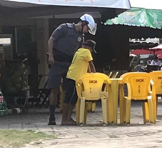 PM olha cardápio com garoto que faz malabarismo em praia de São Vicente.