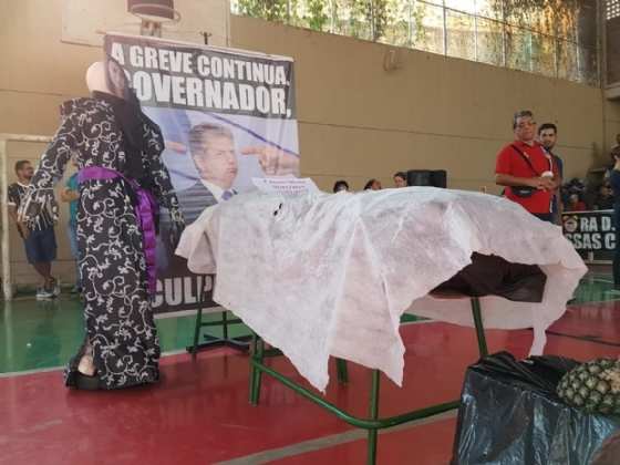 Grevistas simulam velório do governador durante assembleia geral.