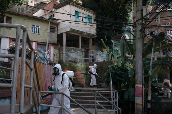 Voluntários pulverizam desinfetante para ajudar a conter a disseminação do novo coronavírus na favela de Babilônia, no Rio de Janeiro, no domingo (12)