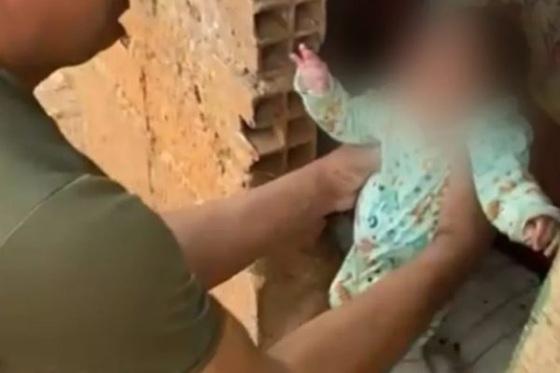  A criança estava deitada dentro de um barraco improvisado com tijolos e madeira. 