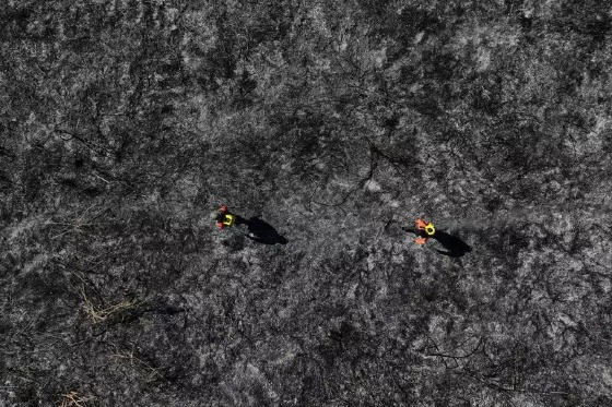 Bombeiros voluntários, membros da Brigada do Alto Pantanal andam por área queimada enquanto trabalham para extinguir o fogo no Pantanal, em Corumbá (MS)