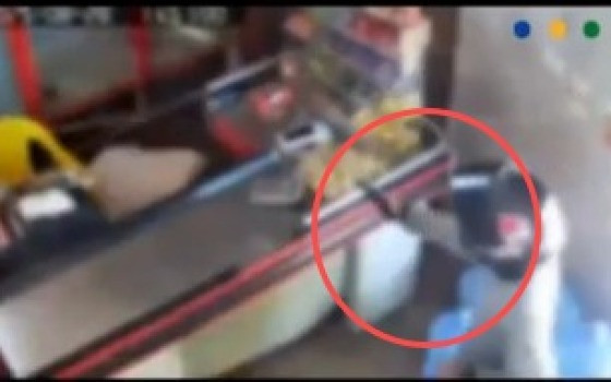 O homem chega a jogar o celular contra o atirador e se esconde atrás do balcão
