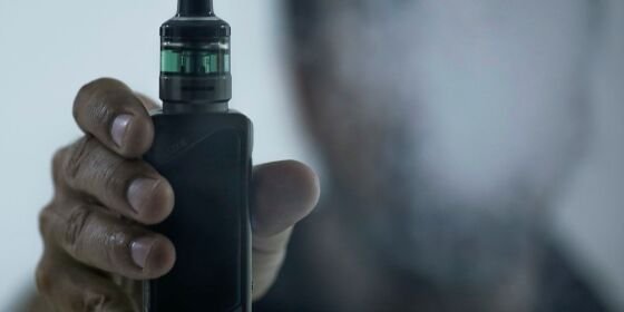 Cigarros eletrônicos em diferentes formatos e cores, expostos em uma mesa.