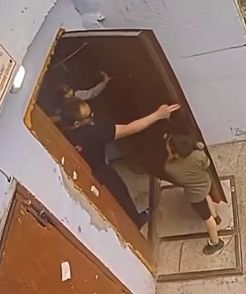 Mesmo sendo empurrado, o menino insiste e segura a porta do local para dificultar a ação do homem