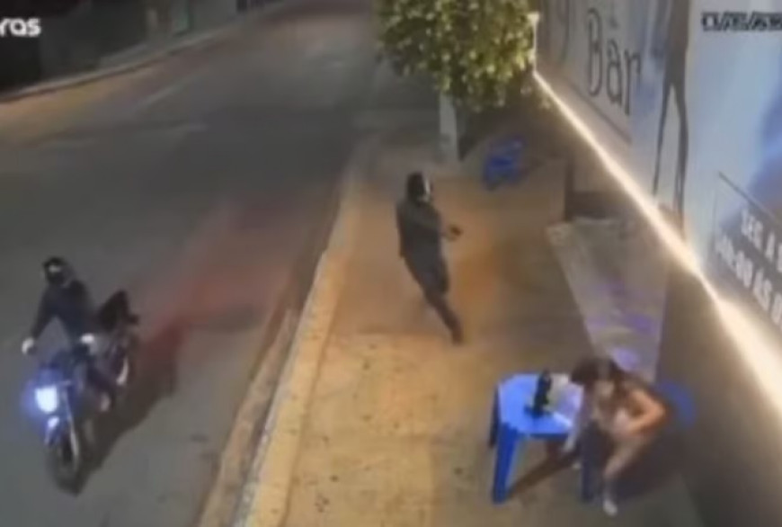 Câmera de segurança registrou o momento em que o atirador desceu da motocicleta e efetuou disparos contra a mulher em frente ao bar.