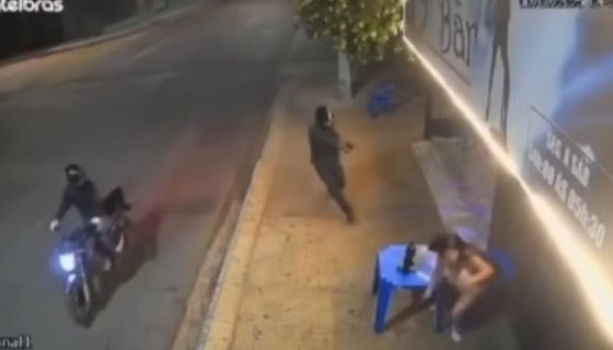 Câmera de segurança registrou o momento em que o atirador desceu da motocicleta e efetuou disparos contra a mulher em frente ao bar.