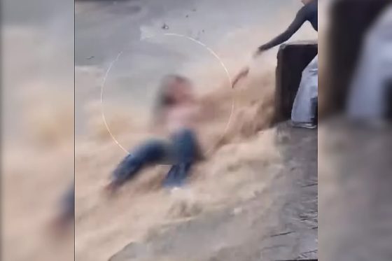 Imagens mostram a jovem sendo levada pela água até bater em um poste, momento em que uma moradora consegue segurá-la pelo braço.