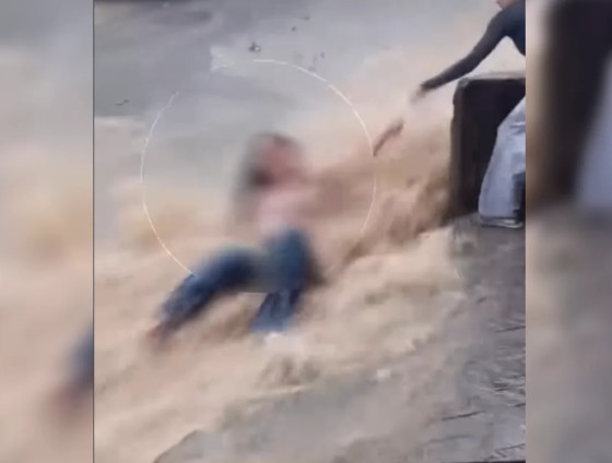Imagens mostram a jovem sendo levada pela água até bater em um poste, momento em que uma moradora consegue segurá-la pelo braço.